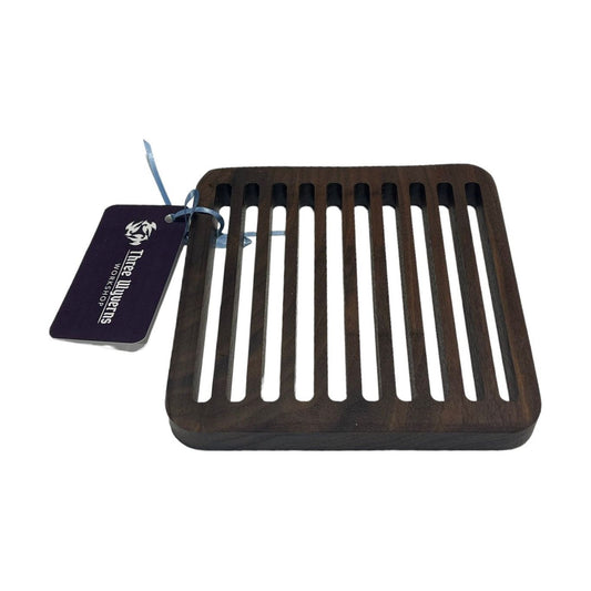 Elevate your dining experience with our Black Walnut Trivet. Handcrafted and timeless, it adds warmth and sophistication to your table. Protects surfaces from heat and serves as a beautiful centerpiece. Measures 6.5" x 6.5" x .75"